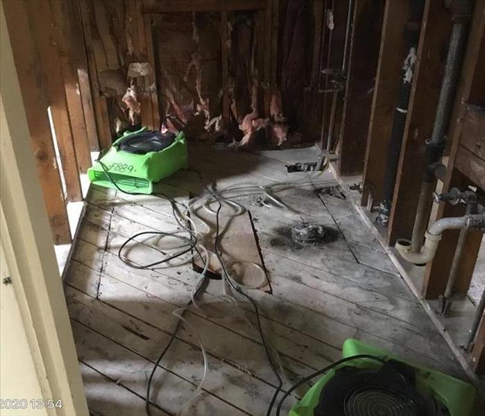 A room with drywall removed and two green fans